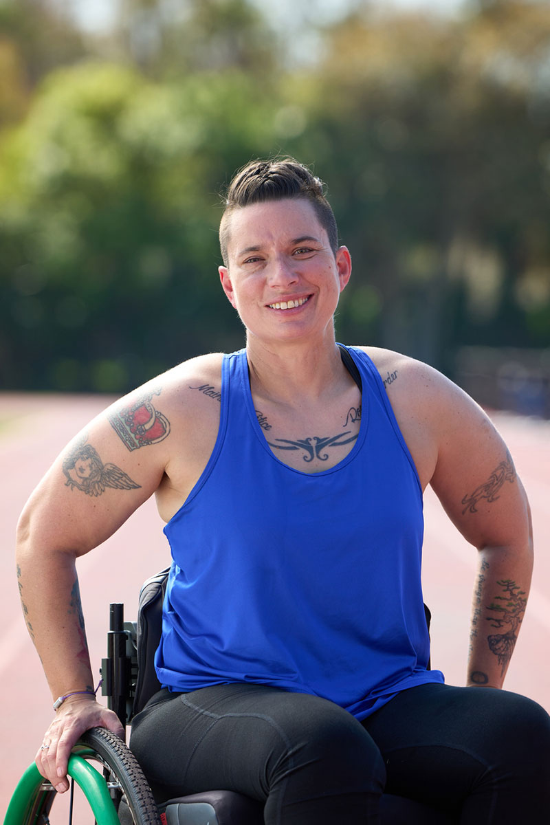 Wounded warrior Beth King sitting in a wheelchair, smiling in a track field.