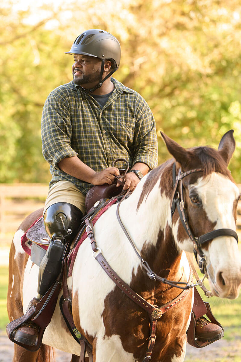 Wounded warrior Chris Gordon riding a horse with his prosthetic leg.