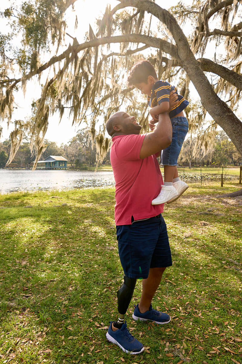 Wounded warrior Chris Gordon holding his son outside and smiling.