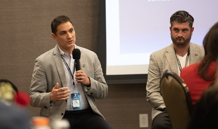 Carl Legge, of Johnson & Johnson, speaks to attendees of Wounded Warrior Project’s Corporate Partners Summit while holding a microphone. 