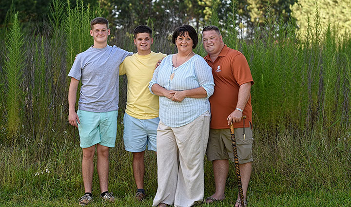 Wounded warrior Tom Marcum stands next to his wife and two sons outside.