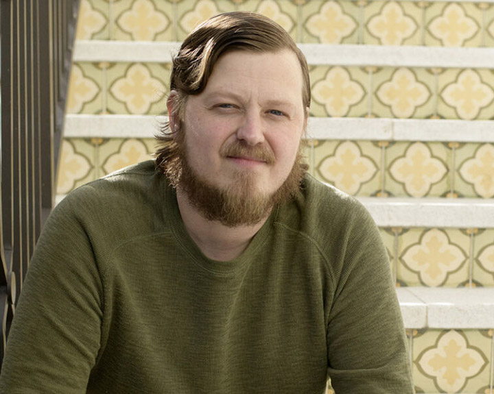 Nick Morrison sits outside on a tiled stairway. 