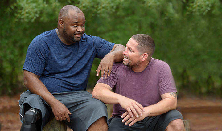 Wounded warrior Chris Gordon sits next to fellow wounded Warrior Manny Colon while talking.