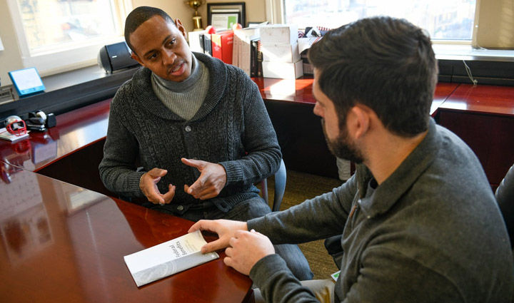 Wounded Warrior Tyshawn Jenkins sitting at a desk discussing Financial Wellness with an advisor.