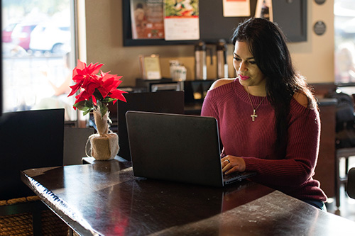 Wounded warrior Yomari Cruz sits at a table while typing on a laptop. 